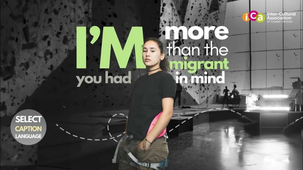 A young woman stands in front of text that reads "I'M more than the migrant in mind".
