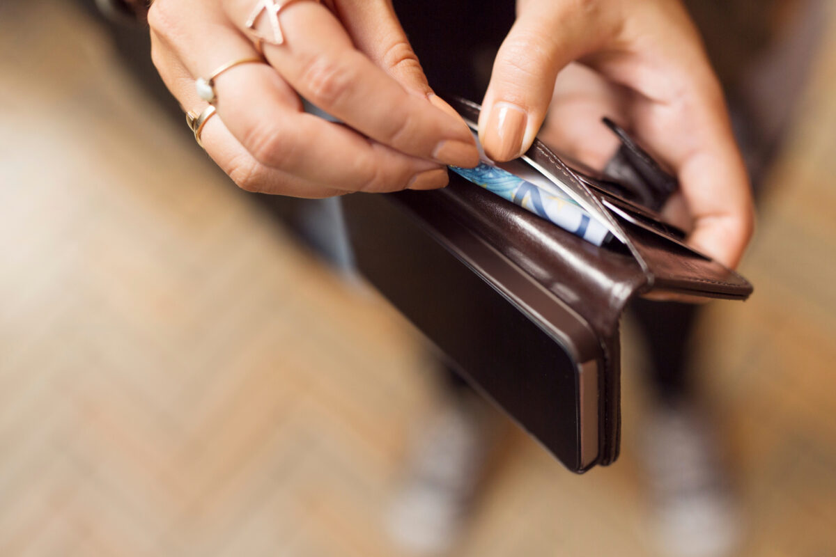 Persons Hands Rings Seen Placing Credit Card Into A person's hands with rings are seen placing a credit card into a brown leather wallet.